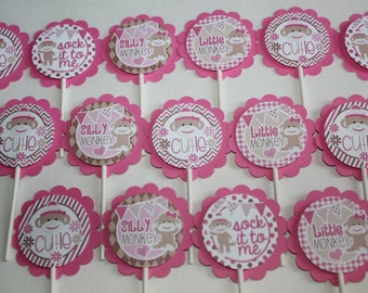 May include: Pink and brown cupcake toppers with a sock monkey theme. Each topper has a scalloped edge and features a sock monkey illustration with phrases like "Cutie", "Silly Monkey", and "Sock it to me".