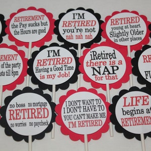 May include: A collection of retirement-themed party decorations. Each decoration features a white circle with a black or red scalloped border, mounted on a stick. Text in red and black reads phrases like "Retired Life is Seven Day Weekends."