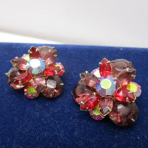 May include: A pair of vintage flower-shaped earrings with red, pink, and iridescent rhinestones.