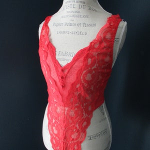 May include: Red lace lingerie bodysuit on a white mannequin. The mannequin has text printed on it, including "Artiste du Roi", "Papier Peints et Tissus", and "Champs-Elysees".