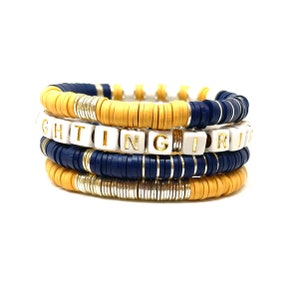 May include: A stack of four bracelets with gold and silver beads, blue and yellow beads, and white letter beads spelling out "FIGHTING GIRL".