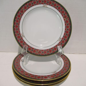 May include: Three red and green patterned ceramic dessert plates with gold trim stacked on top of each other.