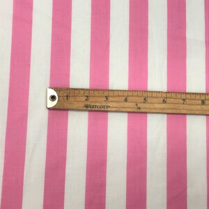 May include: Pink and white striped fabric with a ruler measuring 8 inches.