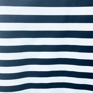 May include: A black and white striped fabric with a subtle wave pattern. The fabric is made of a soft, smooth material.