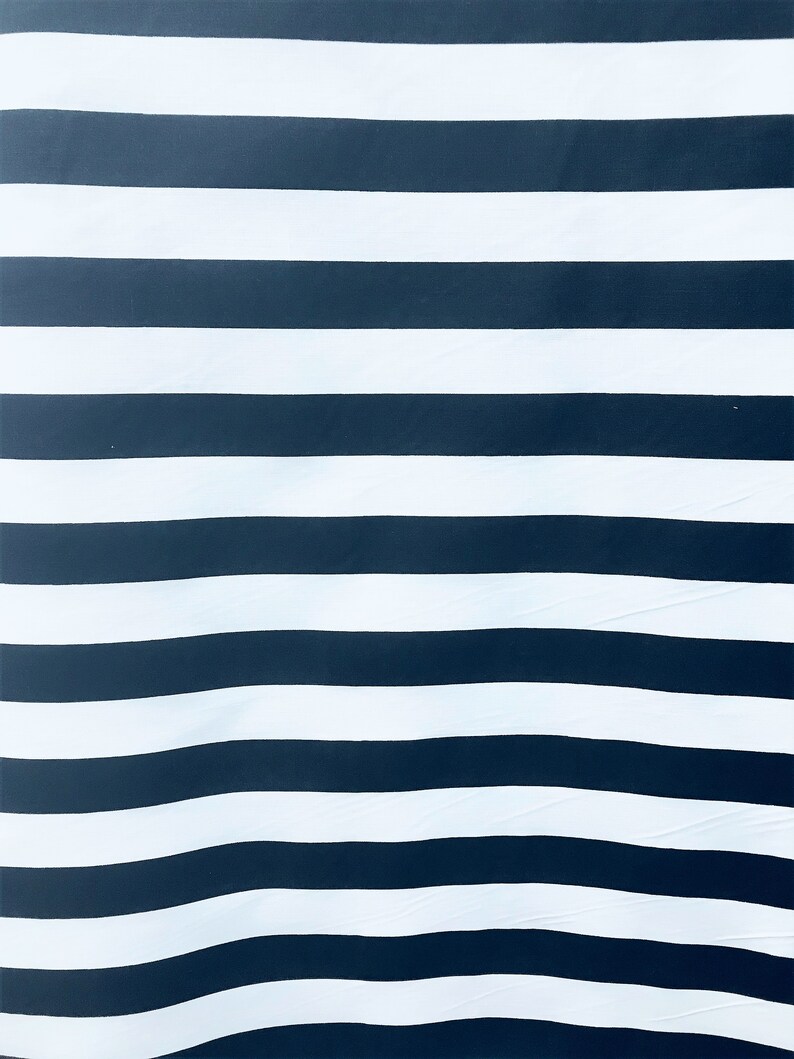 May include: A black and white striped fabric with a subtle wave pattern. The fabric is made of a soft, smooth material.