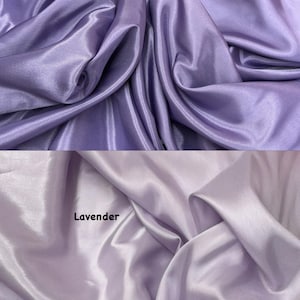 Puede incluir: Dos muestras de tela, una en lila antiguo y otra en lavanda. Las telas est&aacute;n drapeadas, mostrando pliegues y una textura brillante, similar al sat&eacute;n. El texto "Old lilac" y "Lavender" est&aacute; impreso en la tela.