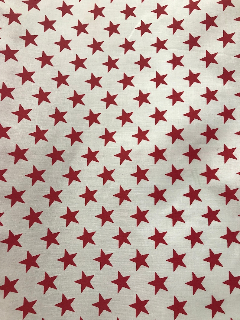 May include: White fabric with a repeating pattern of red stars.