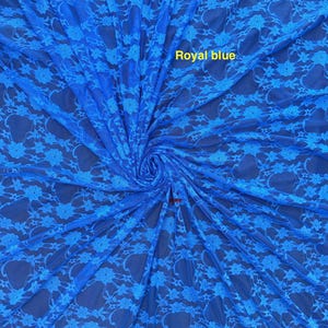 May include: A royal blue lace fabric featuring a repeating floral pattern. The material is gathered in the center, creating a radial effect. The text "Royal blue" is printed in yellow on the upper portion of the fabric surface.