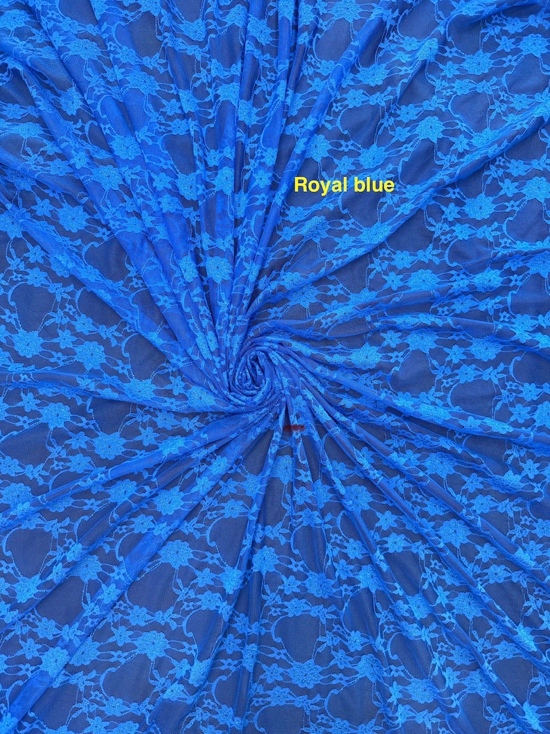 May include: A royal blue lace fabric featuring a repeating floral pattern. The material is gathered in the center, creating a radial effect. The text "Royal blue" is printed in yellow on the upper portion of the fabric surface.