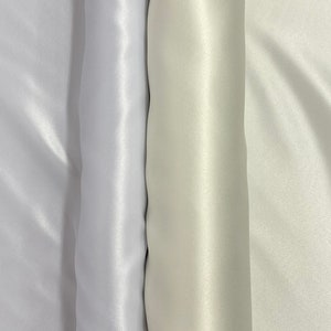 May include: Three rolls of white satin fabric, each with a slightly different shade of white.