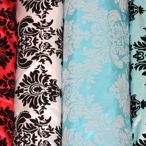 May include: Four rolls of fabric with a black and white damask pattern. The fabric rolls are red, white, light blue, and turquoise.