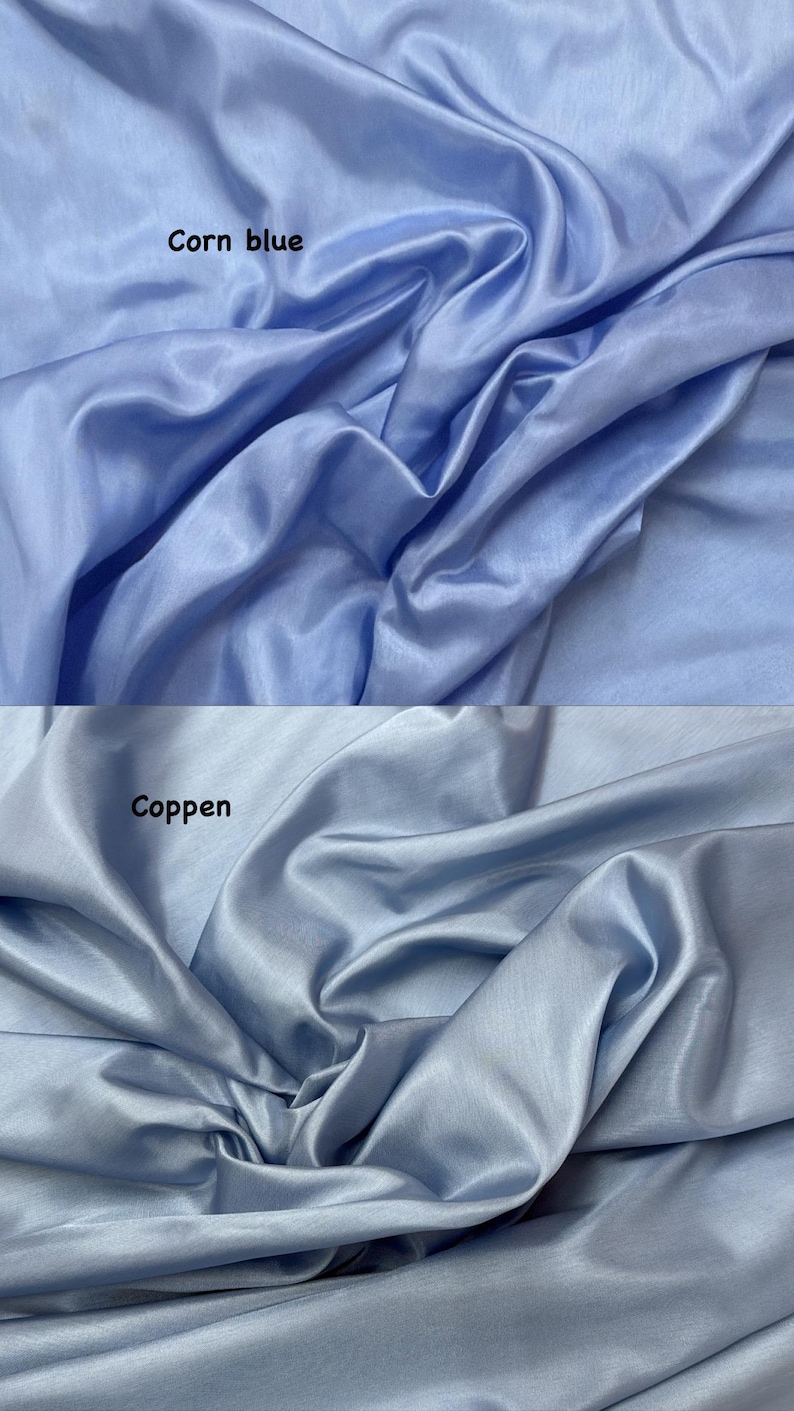 Puede incluir: Dos secciones de tela azul claro con un brillo sedoso. La secci&oacute;n superior est&aacute; etiquetada como "Corn blue", y la secci&oacute;n inferior como "Coppen". La tela est&aacute; drapeada, creando pliegues y sombras suaves, resaltando su textura y color.
