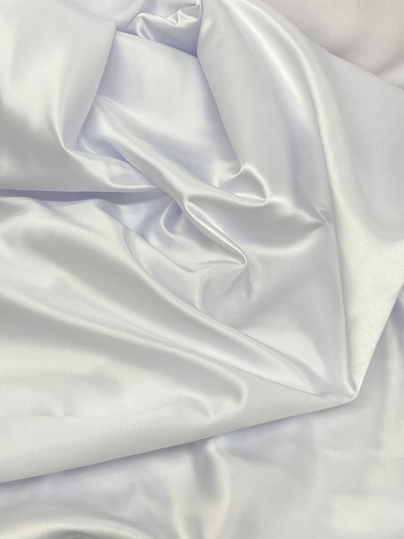 May include: White satin fabric with soft, flowing folds and a smooth, luxurious texture.