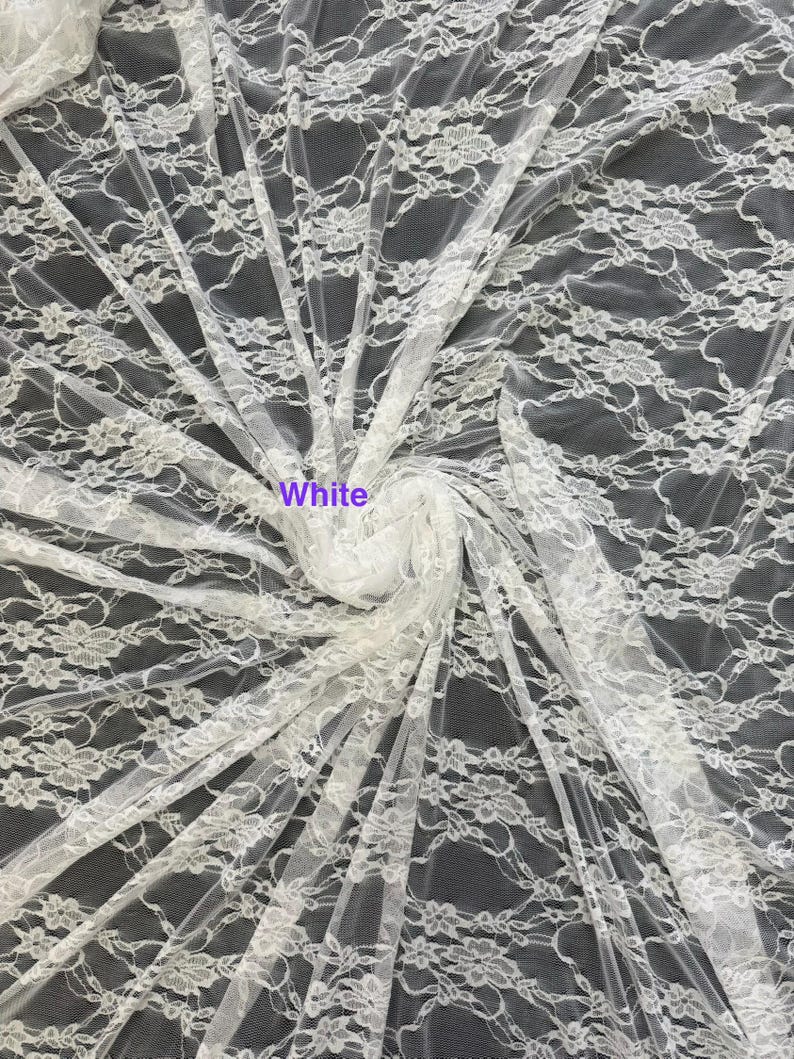 May include: A sheer white lace fabric featuring a repeating floral pattern with delicate scalloped edges and intricate mesh detailing. The fabric is gathered in the center, displaying the lightweight texture and the word White printed on it.