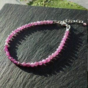 May include: A delicate pink gemstone bracelet with a silver clasp and extender chain. The bracelet is made of small, round beads and is perfect for everyday wear.