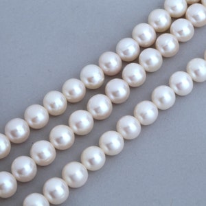 Peut inclure: Un collier de perles blanches, disposées en trois rangées, chaque perle étant espacée uniformément.