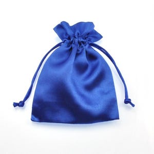 May include: A royal blue satin drawstring pouch. The bag is gathered at the top with a matching blue drawstring. The pouch is on a white background. The bag is likely used for jewellery, gifts, or small items.
