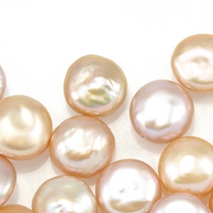 Könnte beinhalten: Eine Sammlung runder, flacher Perlen in zarten Rosa- und Pfirsichtönen. Die Perlen haben einen irisierenden Glanz.