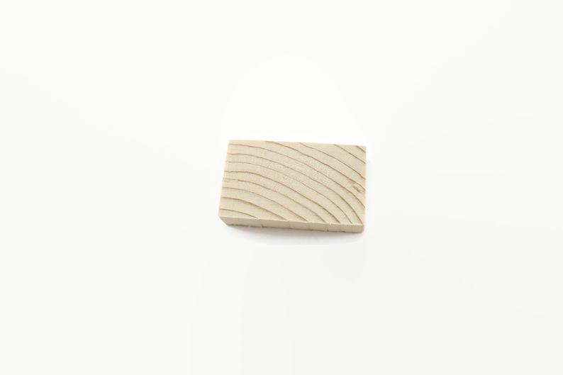 May include: A small, rectangular block of wood with a light brown color and a grain pattern.