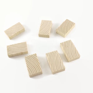 May include: Eight wooden dominoes with a light brown color and a wood grain pattern. The dominoes are arranged in a circle on a white surface.