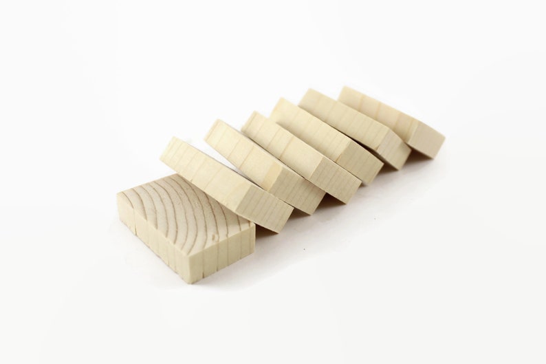 May include: Six unfinished wooden blocks stacked in a staggered pattern on a white surface. The blocks are rectangular and have a natural wood color.
