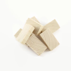May include: A pile of six unfinished wooden blocks with a grooved pattern on the surface. The blocks are light brown in color and are arranged in a random pattern.