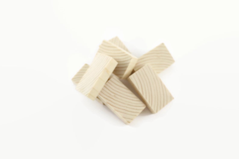May include: A pile of six unfinished wooden blocks with a grooved pattern on the surface. The blocks are light brown in color and are arranged in a random pattern.