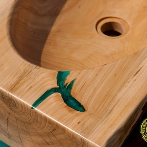 K&ouml;nnte beinhalten: Ein Waschbecken aus Holz mit einem gr&uuml;nen Epoxidharzeinleger. Das Waschbecken ist aus einem einzigen St&uuml;ck Holz gefertigt und hat ein nat&uuml;rliches, rustikales Aussehen. Das Waschbecken ist f&uuml;r die Verwendung in einem Badezimmer oder einer K&uuml;che konzipiert.