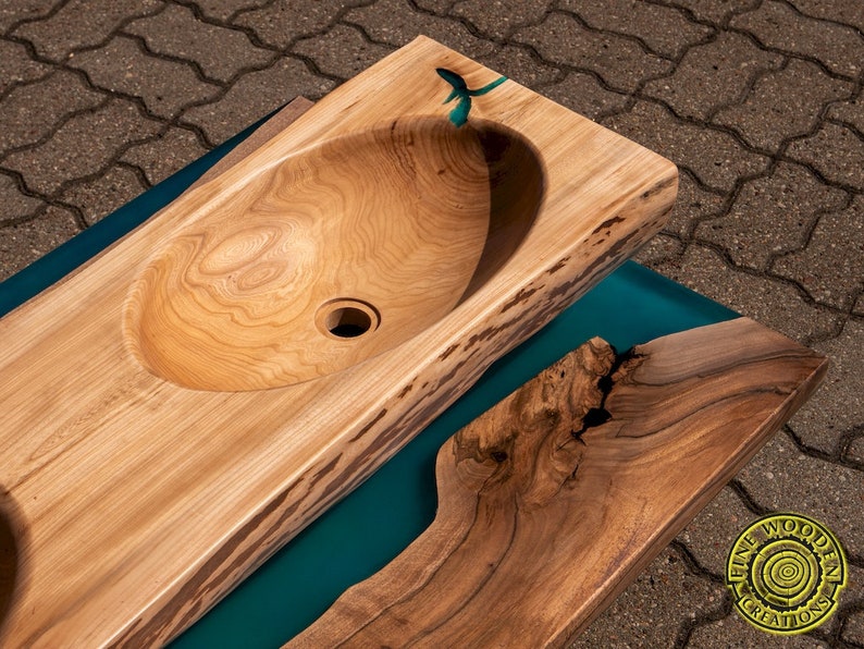 K&ouml;nnte beinhalten: Eine Holztheke mit einem ausgeh&ouml;hlten Waschbecken und einer Einlage aus t&uuml;rkisfarbenem Epoxidharz. Die Arbeitsplatte besteht aus einem einzigen St&uuml;ck Holz mit nat&uuml;rlichen Kanten und einer Live-Edge-Oberfl&auml;che.