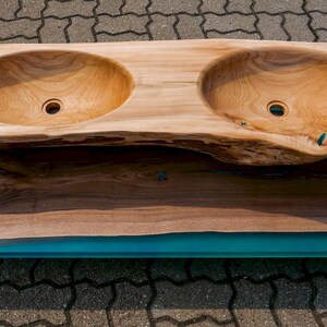 K&ouml;nnte beinhalten: Doppelwaschtisch aus einer gro&szlig;en Holzplatte mit einem t&uuml;rkisfarbenen Harzeinleger. Die Waschbecken sind aus dem Holz geschnitzt und haben eine nat&uuml;rliche Oberfl&auml;che.