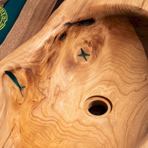 K&ouml;nnte beinhalten: Nahaufnahme eines Waschbeckens aus Holz mit einer Einlage aus t&uuml;rkisfarbenem Harz. Das Waschbecken hat eine runde Form mit einem Loch in der Mitte f&uuml;r einen Abfluss.