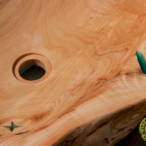 K&ouml;nnte beinhalten: Ein Waschbecken aus Holz mit einer Einlage aus t&uuml;rkisfarbenem Harz. Das Waschbecken hat ein rundes Abflussloch und eine einzigartige, nat&uuml;rliche Form.