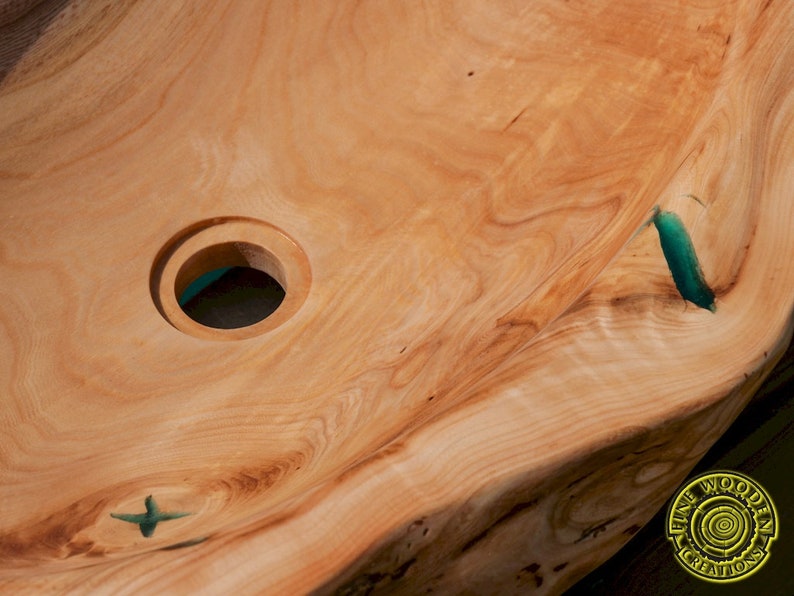 K&ouml;nnte beinhalten: Ein Waschbecken aus Holz mit einer Einlage aus t&uuml;rkisfarbenem Harz. Das Waschbecken hat ein rundes Abflussloch und eine einzigartige, nat&uuml;rliche Form.