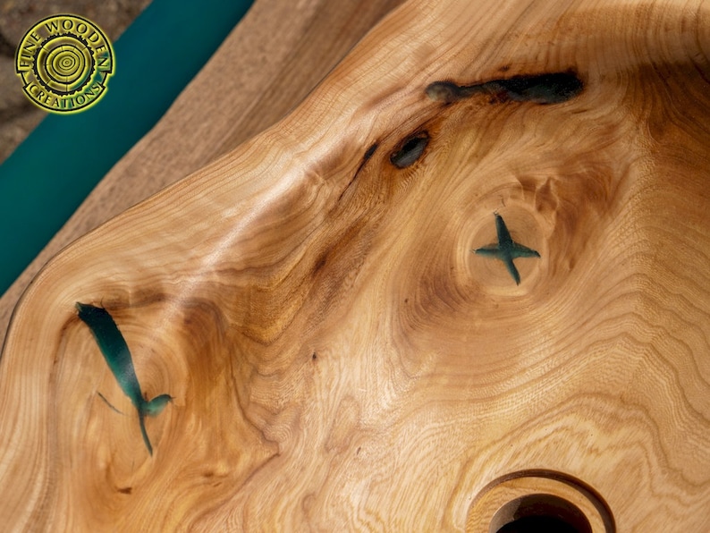 K&ouml;nnte beinhalten: Ein Waschbecken aus Holz mit einer nat&uuml;rlichen Holzmaserung. Das Waschbecken hat eine einzigartige Form und verf&uuml;gt &uuml;ber zwei kleine gr&uuml;ne Epoxidharz-Einlagen.