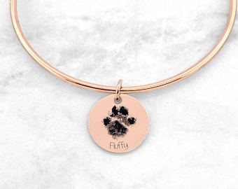 Könnte beinhalten: Roségoldenes Armkettchen mit einem runden Anhänger, der eine schwarze Pfote und den eingravierten Namen "Fluffy" zeigt.