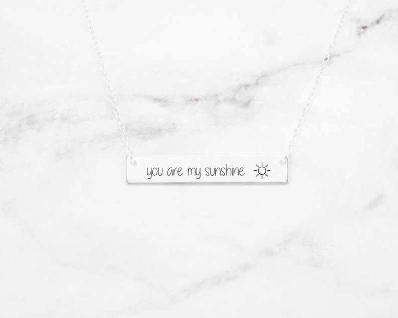 以下が含まれることがあります： 太陽のシンボルが付いた「you are my sunshine」と書かれたバーペンダントが付いたシルバーネックレス