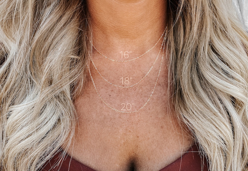 May include: Three gold chain necklaces layered on a person's neck. The chains are labeled with their lengths: 16 inches, 18 inches, and 20 inches.