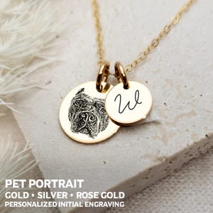 Puede incluir: Collar de oro con dos colgantes redondos. Un colgante presenta una imagen grabada en blanco y negro de la cara de un perro. El otro colgante tiene una inicial "W" manuscrita grabada en él.  Retrato de mascota Oro, Plata, Oro rosa Grabado de inicial personalizado.