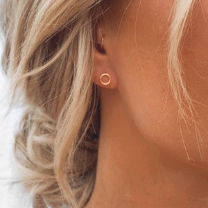 May include: A pair of gold hoop earrings with a simple, minimalist design. The earrings are small and delicate, making them a perfect choice for everyday wear.