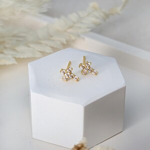 May include: A pair of gold cross earrings with clear cubic zirconia stones.