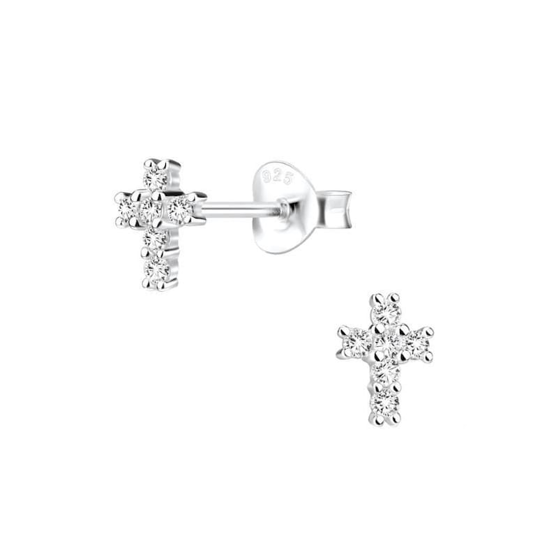 May include: A pair of silver cross stud earrings with small clear cubic zirconia stones.