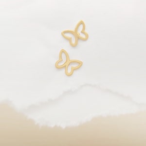 May include: Two gold butterfly shaped earrings on a white background.