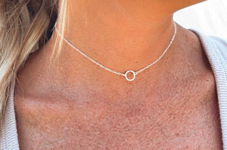 May include: A silver chain necklace with a simple circle pendant.