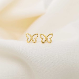 May include: A pair of gold butterfly stud earrings. The earrings are small and delicate, with a simple design.