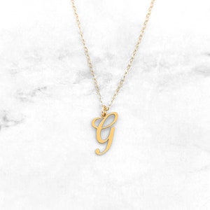 May include: A gold-tone necklace with a cursive letter G pendant.