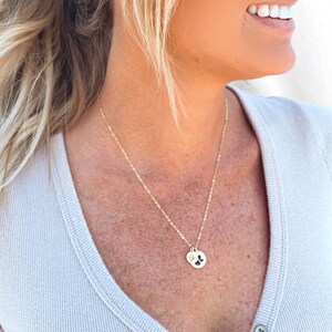 May include: A gold chain necklace with a small round pendant featuring a paw print design.