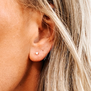 May include: A close-up of a person's ear with a small, round, silver stud earring.