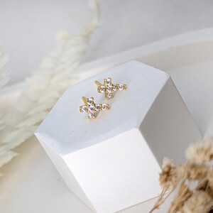 May include: A pair of gold cross earrings with clear cubic zirconia stones.