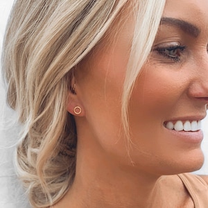 May include: A close-up of a person's ear with a small, gold, hoop earring.