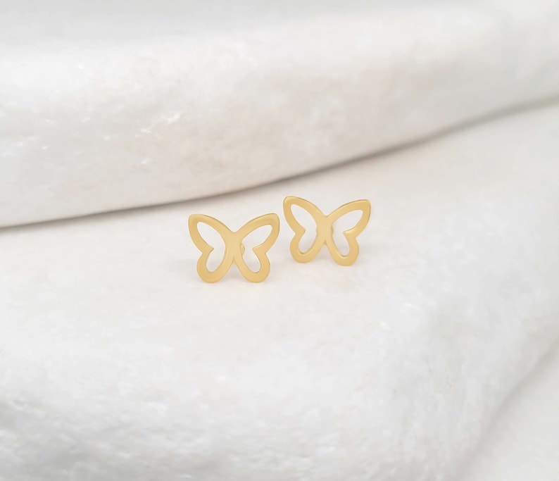 May include: A pair of gold butterfly earrings. The earrings are small and delicate, and they are perfect for adding a touch of elegance to any outfit.